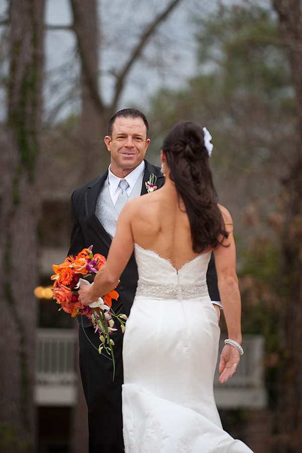 bride and groom's first look at each other on their wedding day - bride is wearing white dress with embellishments and holding orange,coral, and dark pink bouquet - photo by Houston based wedding photographer Adam Nyholt